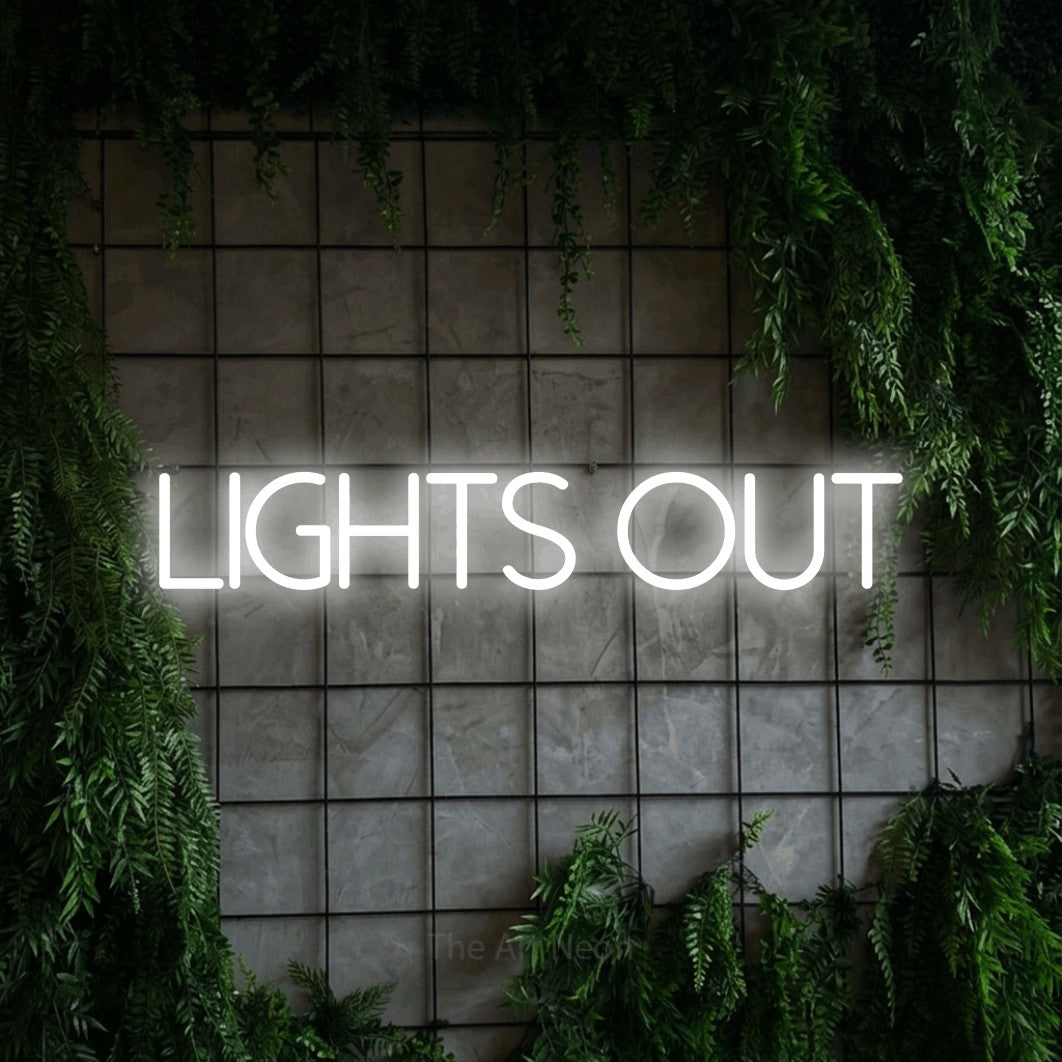 Cool white LED neon sign reading "Lights Out" against a green grid wall with foliage for bedroom décor