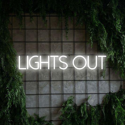 Cool white LED neon sign reading "Lights Out" against a green grid wall with foliage for bedroom décor
