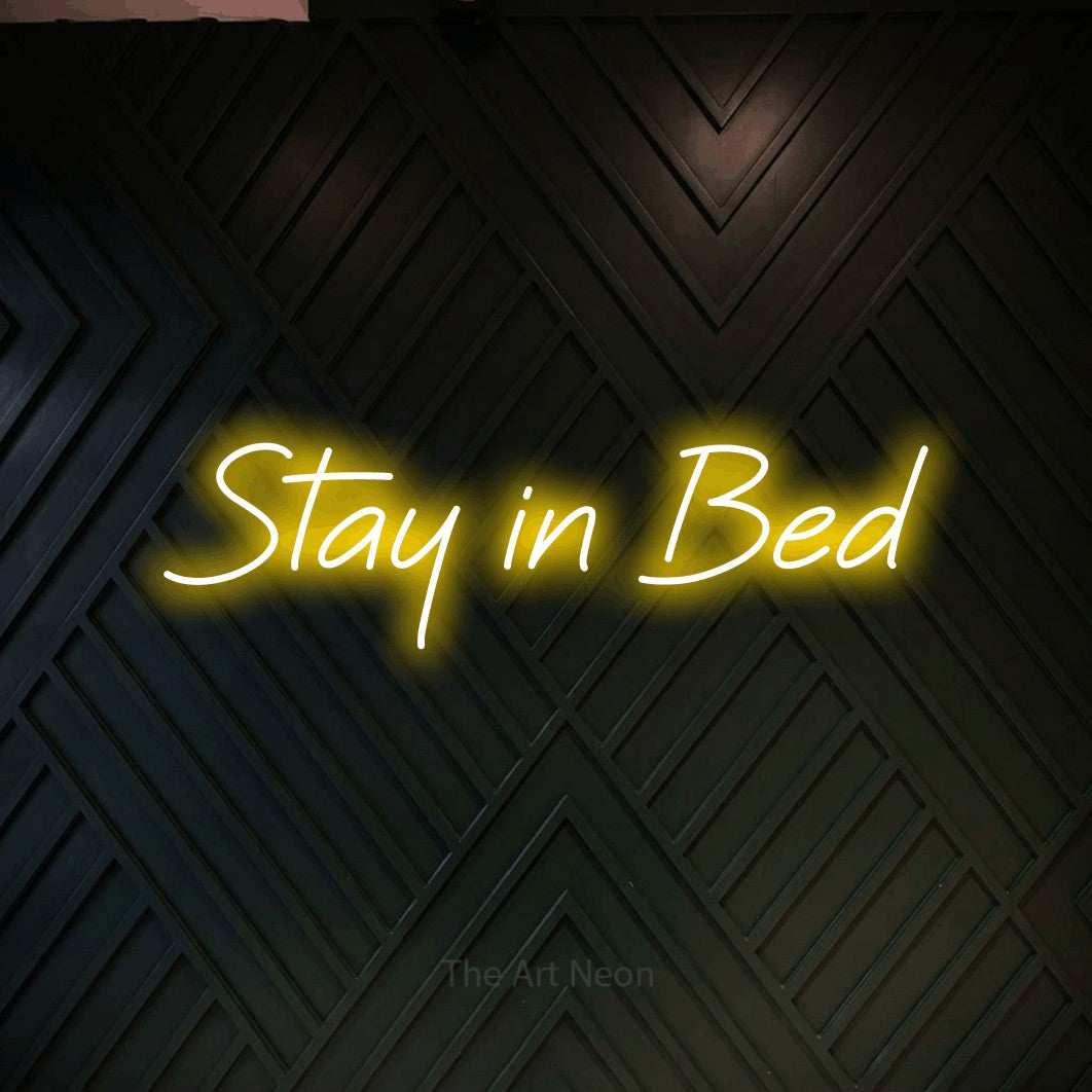 Enseigne néon à DEL à lumière jaune, affichant « Stay in Bed » sur un mur géométrique en bois foncé, pour décorer une chambre