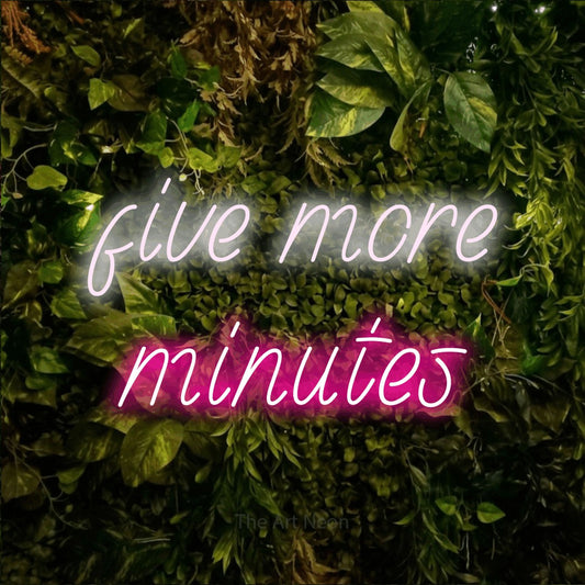 Hot pink and cool white LED neon sign reading "Five More Minutes" against a textured moss and foliage wall for bedroom décor