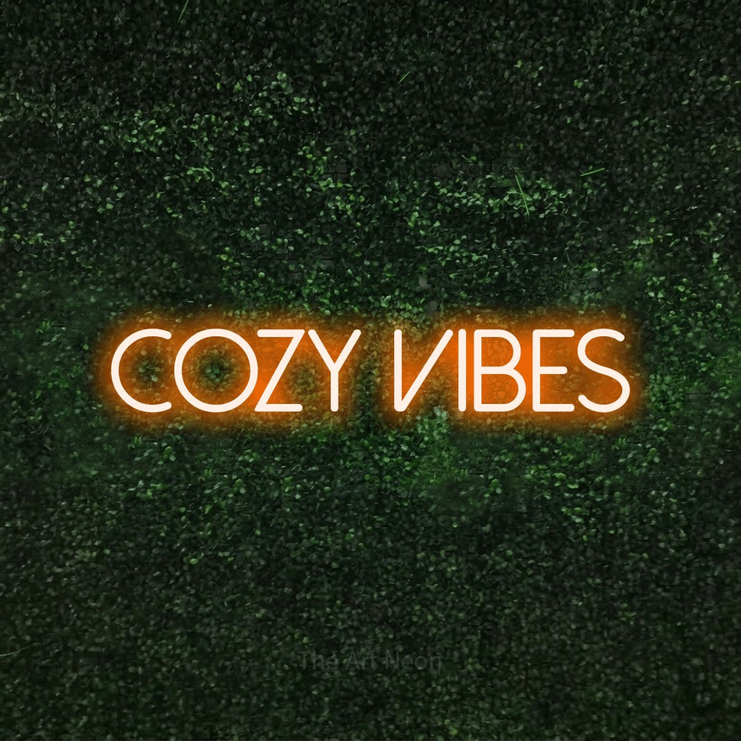 Enseigne néon à DEL à lumière orange, affichant « Cozy Vibes » sur un mur texturé de mousse verte, pour décorer une chambre