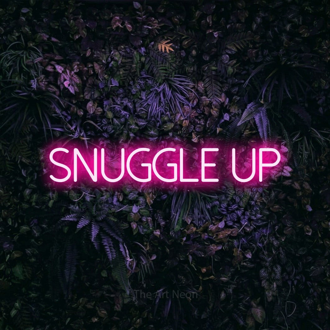Hot pink LED neon sign reading "Snuggle Up" against a purple floral wall for bedroom décor