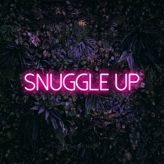 Hot pink LED neon sign reading "Snuggle Up" against a purple floral wall for bedroom décor