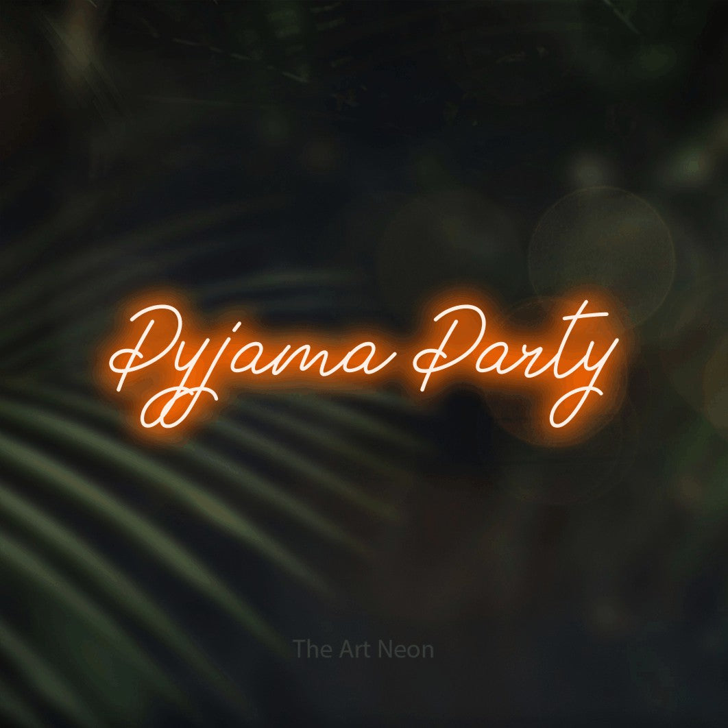 Orange script-style LED neon sign reading "Pyjama Party" against dark blurred palm leaves for bedroom décor