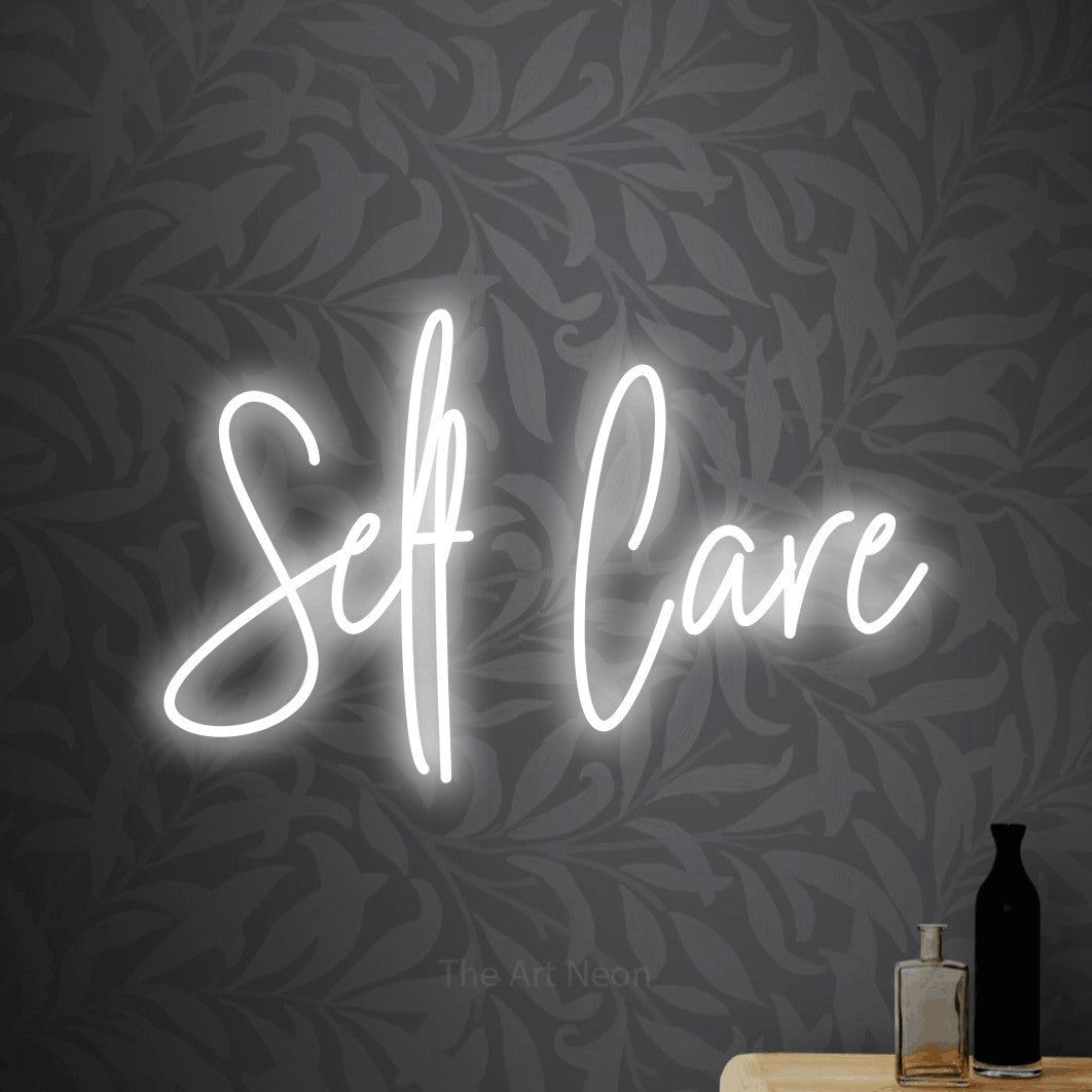 Cool white script-style LED neon sign reading "Self Care" against light grey floral wallpaper for bedroom décor
