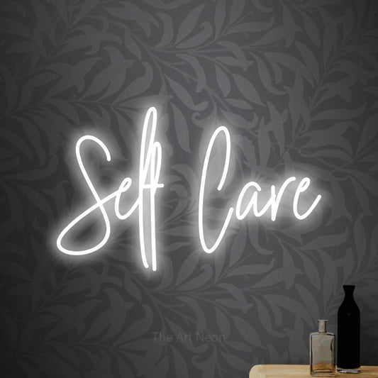 Cool white script-style LED neon sign reading "Self Care" against light grey floral wallpaper for bedroom décor