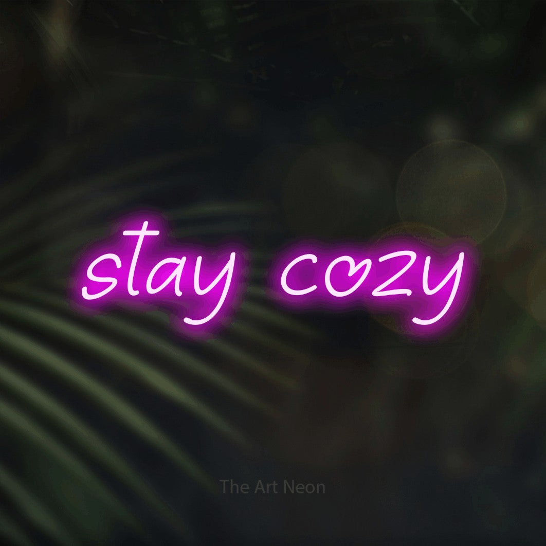 Pink LED neon sign reading "Stay Cozy" against dark blurred palm leaves for bedroom décor