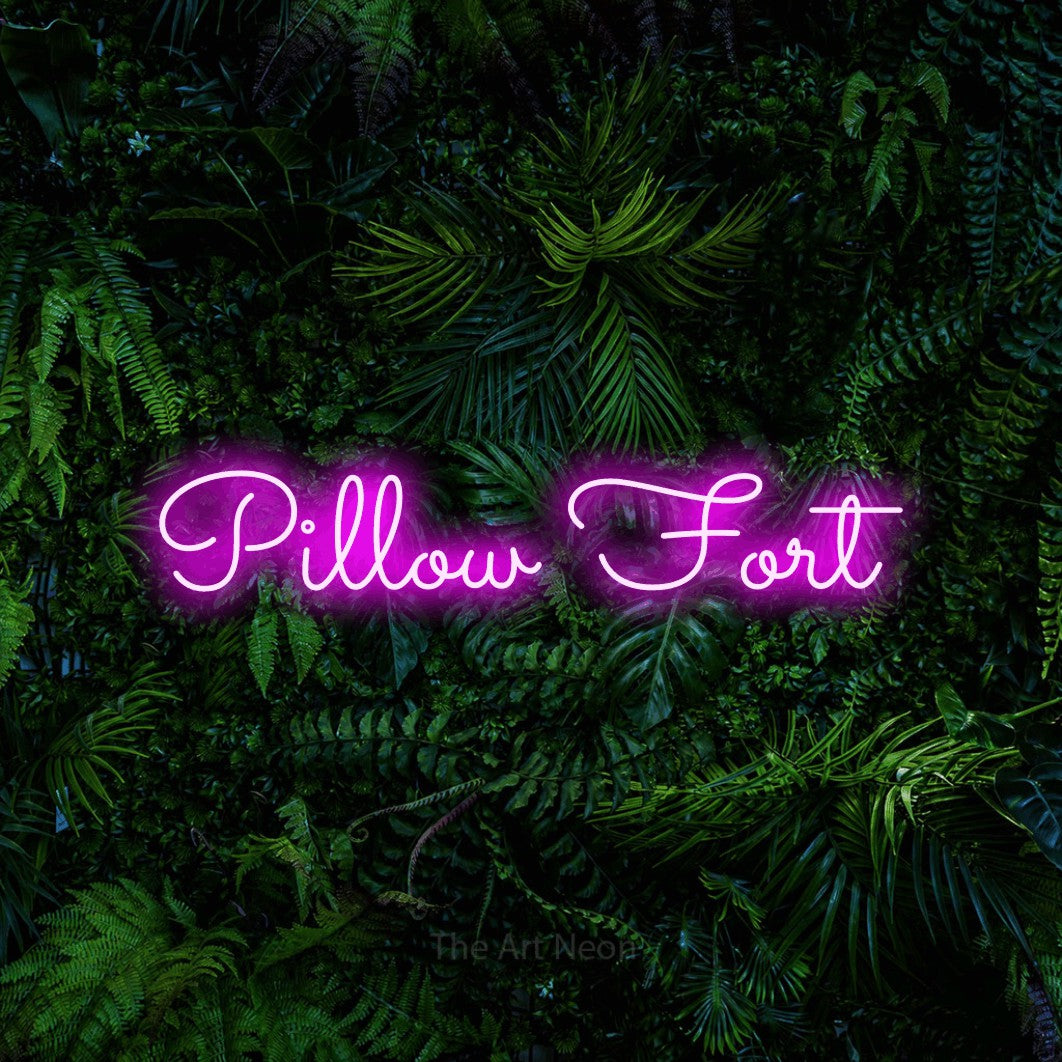 Pink LED neon sign reading "Pillow Fort" against a dense tropical foliage wall for bedroom décor