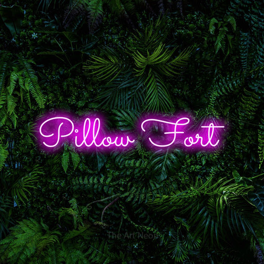 Pink LED neon sign reading "Pillow Fort" against a dense tropical foliage wall for bedroom décor