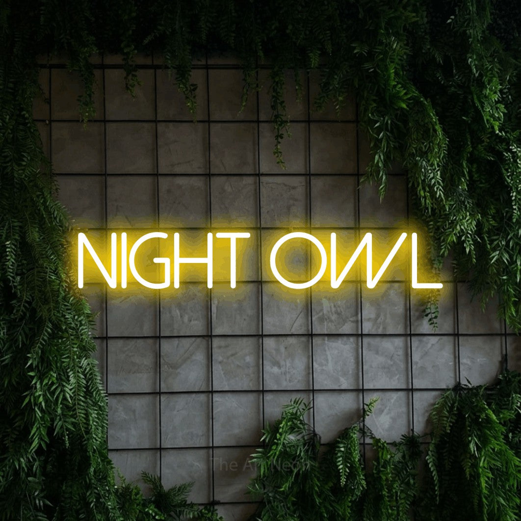 Yellow LED neon sign reading "Night Owl" against a green grid wall with foliage for bedroom décor
