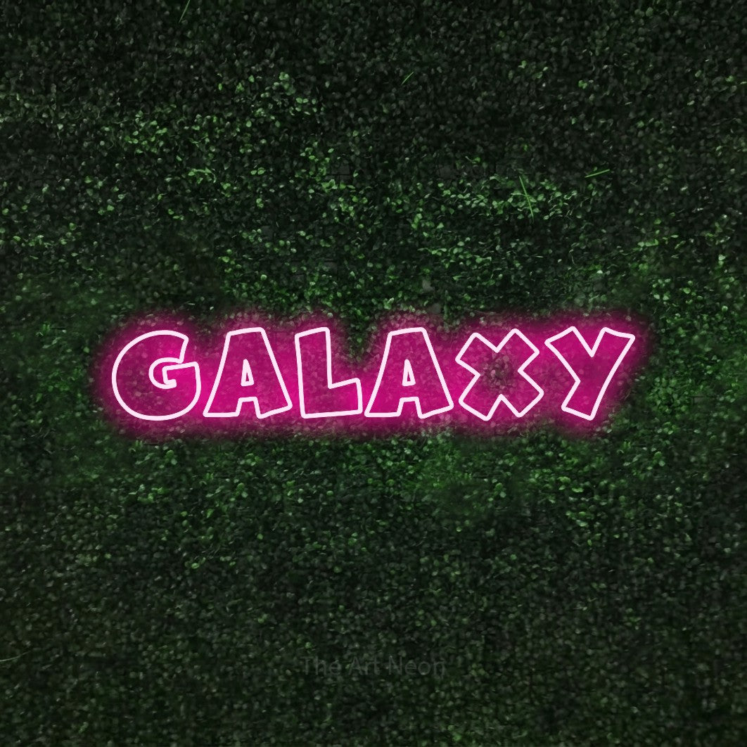Hot pink outline-style LED neon sign reading "Galaxy" against a textured green moss wall for bedroom décor