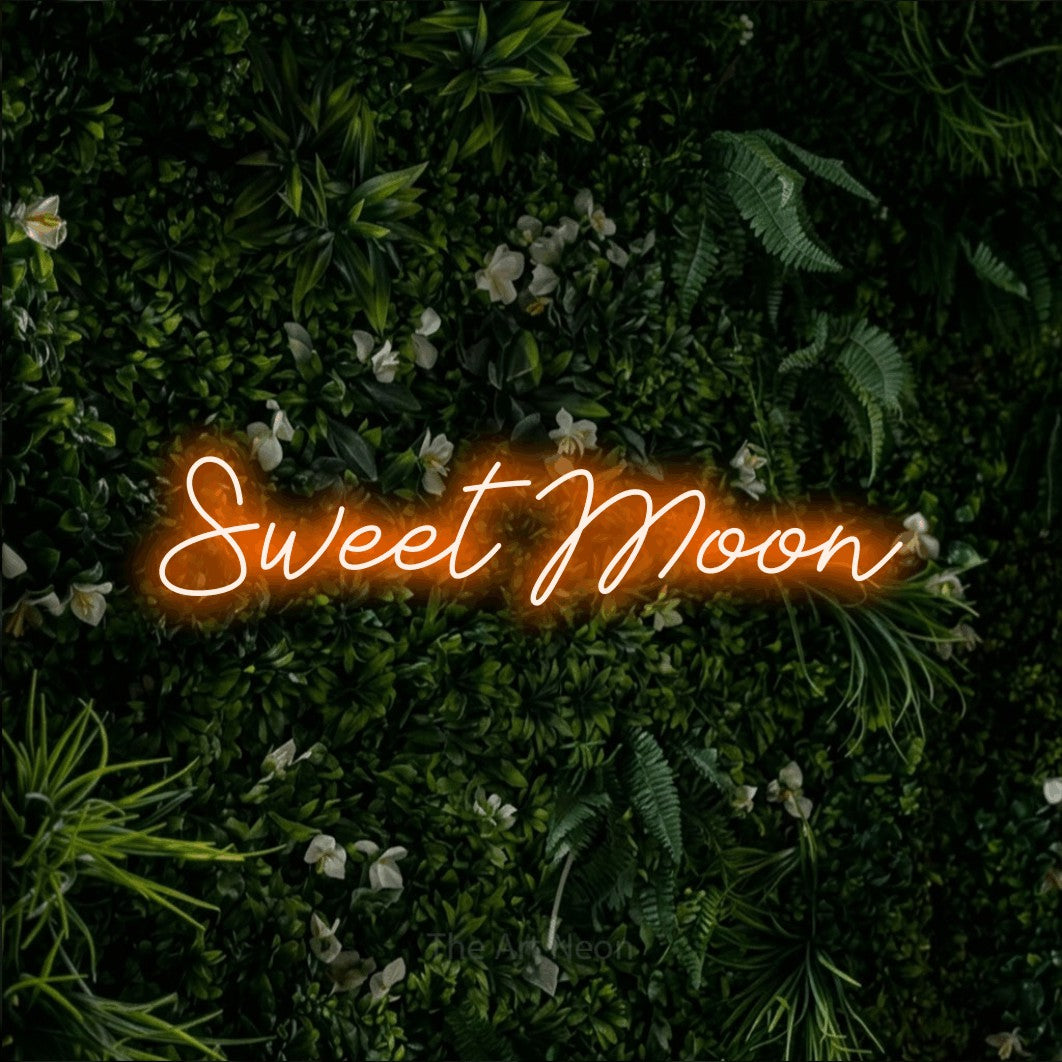 Orange script-style LED neon sign reading "Sweet Moon" against a leafy green wall for bedroom décor