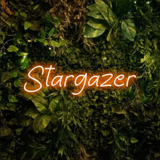 Orange LED neon sign reading "Stargazer" against a textured moss and foliage wall for bedroom décor