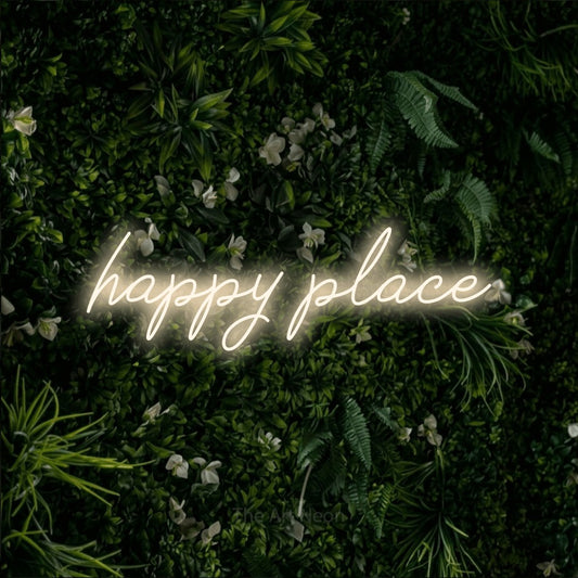 Warm white script-style LED neon sign reading "Happy Place" against a leafy green wall for bedroom décor