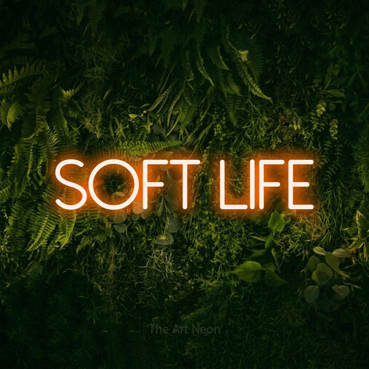 Orange LED neon sign reading "Soft Life" against a moss-covered green wall for bedroom décor