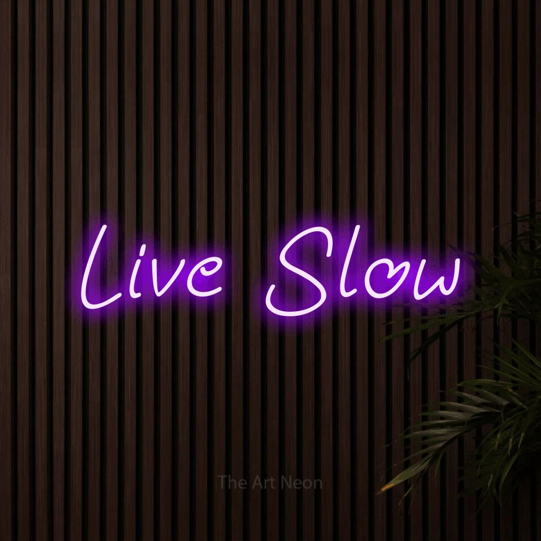 Purple LED neon sign reading "Live Slow" against dark wooden slats for bedroom décor