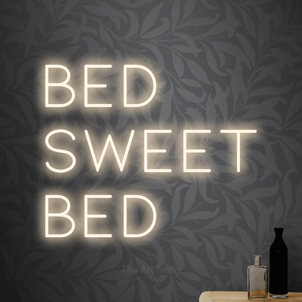 Warm white LED neon sign reading "Bed Sweet Bed" against light grey floral wallpaper for bedroom décor