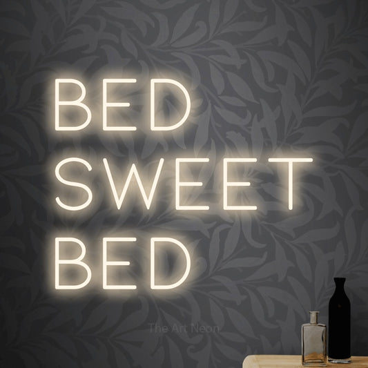 Warm white LED neon sign reading "Bed Sweet Bed" against light grey floral wallpaper for bedroom décor