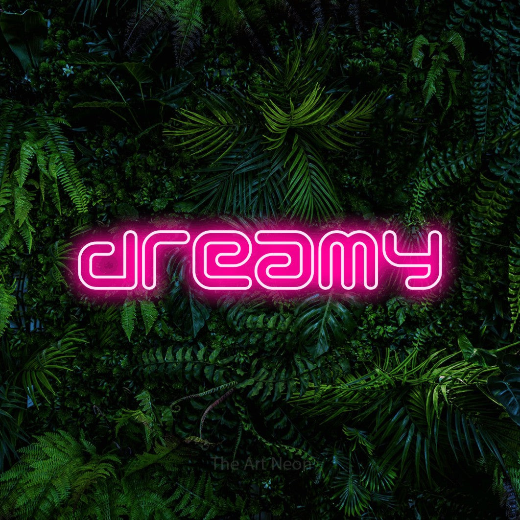 Hot pink outline-style LED neon sign reading "Dreamy" against a dense tropical foliage wall for bedroom décor