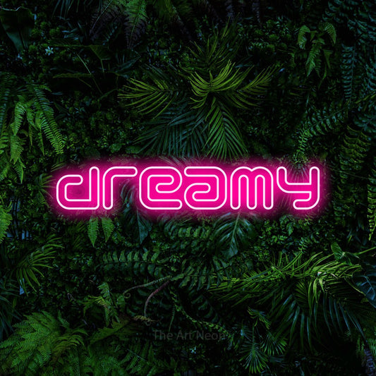 Hot pink outline-style LED neon sign reading "Dreamy" against a dense tropical foliage wall for bedroom décor