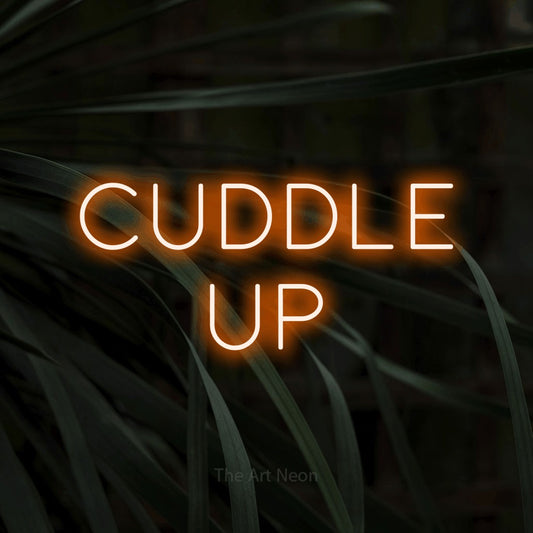Orange LED neon sign reading "Cuddle Up" against dark tropical leaves for bedroom décor