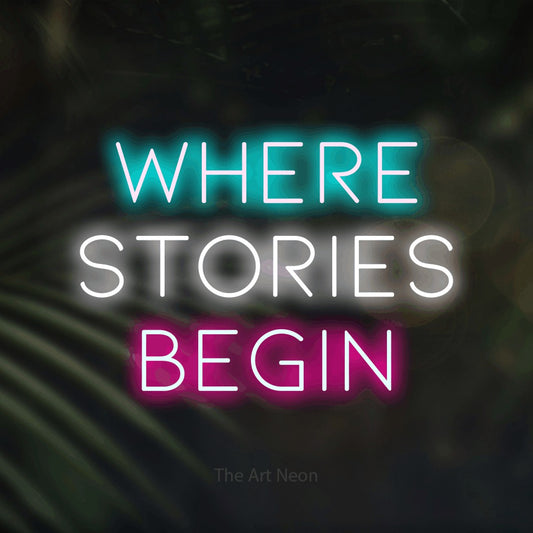 Enseigne néon à DEL à lumière multicolore, affichant « Where Stories Begin » sur des feuilles de palmier foncées et floues, pour décorer un salon