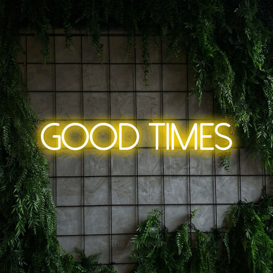 Enseigne néon à DEL à lumière jaune, affichant « Good Times » sur un mur quadrillé vert avec du feuillage, pour décorer un salon