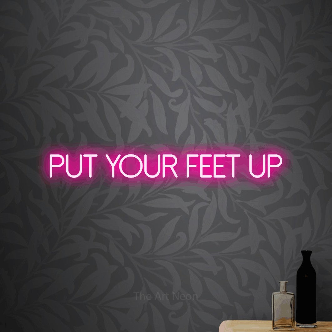 Hot pink LED neon sign reading "Put Your Feet Up" against light grey floral wallpaper for living room décor