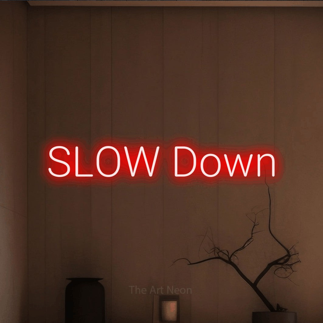Red LED neon sign reading "Slow Down" against a warm brown wall for living room décor