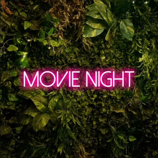 Hot pink LED neon sign reading "Movie Night" against a textured moss and foliage wall for living room décor