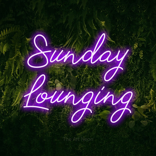 Purple script-style LED neon sign reading "Sunday Lounging" against a moss-covered green wall for living room décor