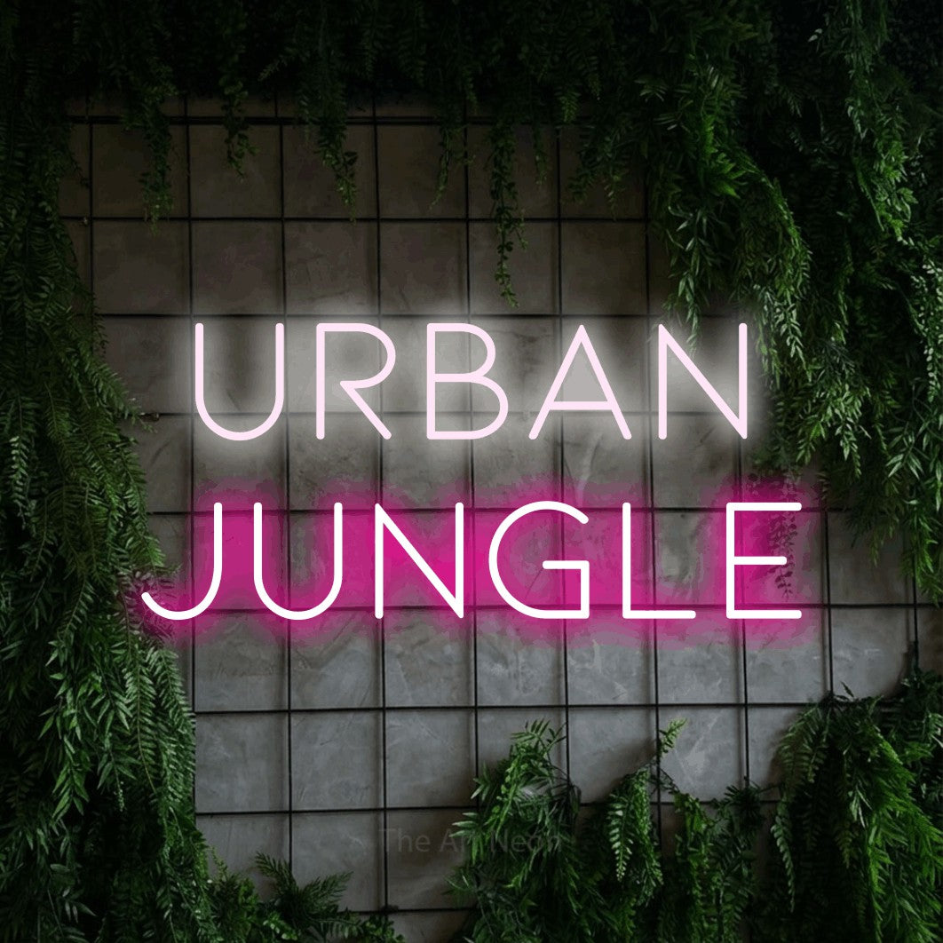 Hot pink and cool white LED neon sign reading "Urban Jungle" against a green grid wall with foliage for living room décor