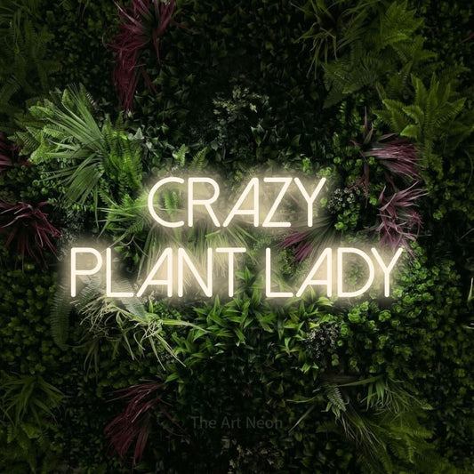 Warm white LED neon sign reading "Crazy Plant Lady" against a lush garden wall with pink flowers for living room décor