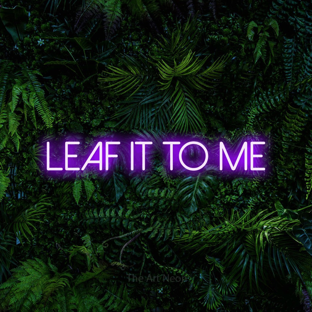 Purple LED neon sign reading "Leaf It to Me" against a dense tropical foliage wall for living room décor