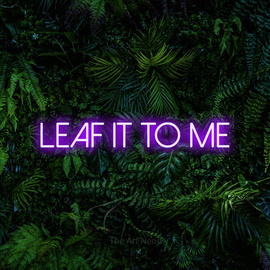Purple LED neon sign reading "Leaf It to Me" against a dense tropical foliage wall for living room décor