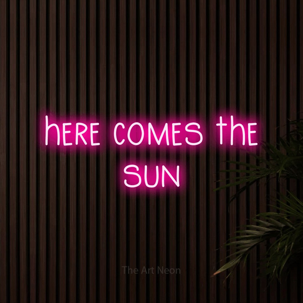 Hot pink LED neon sign reading "Here Comes the Sun" against dark wooden slats for living room décor