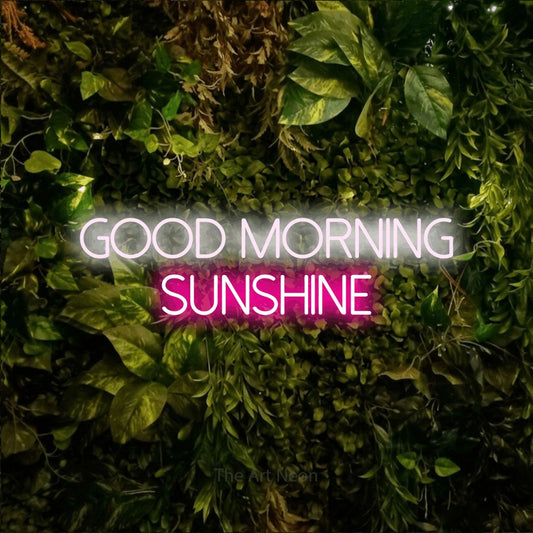 Hot pink and cool white LED neon sign reading "Good Morning Sunshine" against a textured moss and foliage wall
