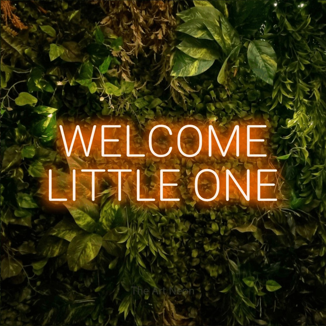Enseigne néon à DEL à lumière orange, affichant « Welcome Little One » sur un mur texturé de mousse et de feuillage, pour décorer une chambre de bébé