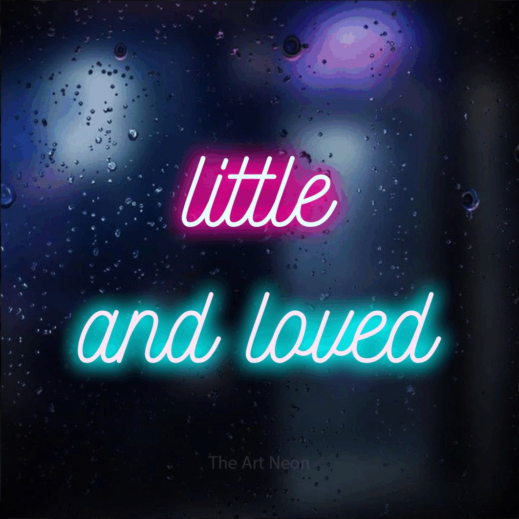 Enseigne néon à DEL à lumière bleu glacier et rose vif, de style manuscrit, affichant « Little and Loved » sur un arrière-plan bokeh bleu foncé