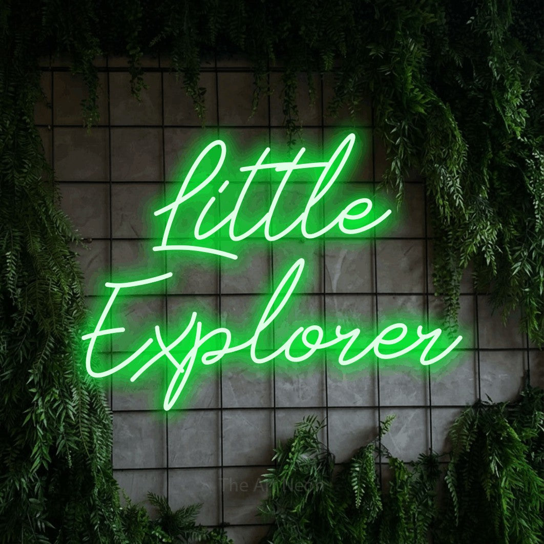 Enseigne néon à DEL à lumière verte, de style manuscrit, affichant « Little Explorer » sur un mur quadrillé vert avec du feuillage, pour décorer une chambre de bébé