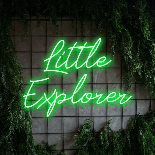 Enseigne néon à DEL à lumière verte, de style manuscrit, affichant « Little Explorer » sur un mur quadrillé vert avec du feuillage, pour décorer une chambre de bébé
