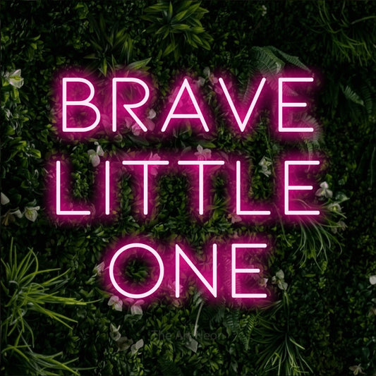 Enseigne néon à DEL à lumière rose vif, affichant « Brave Little One » sur un mur de feuillage vert, pour décorer une chambre de bébé
