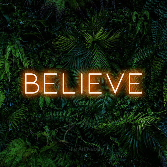 Enseigne néon à DEL à lumière orange, de style contour, affichant « Believe » sur un mur de feuillage tropical dense, pour décorer une chambre de bébé