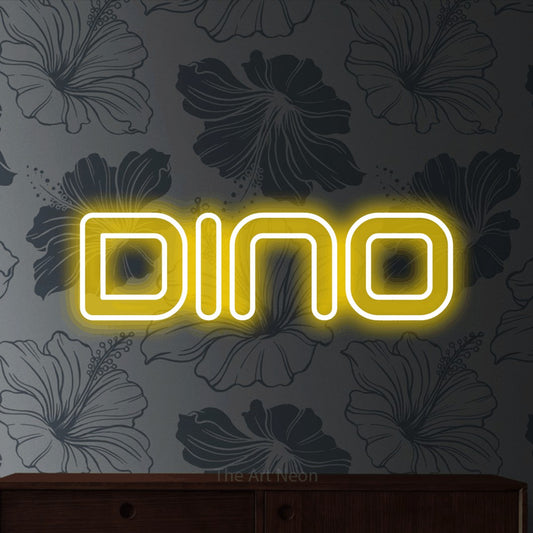 Yellow outline-style LED neon sign reading "Dino" against grey floral wallpaper for nursery décor