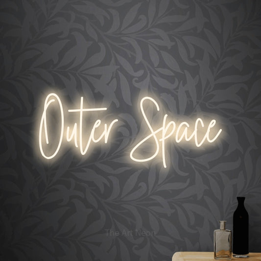 Warm white script-style LED neon sign reading "Outer Space" against light grey floral wallpaper for nursery décor