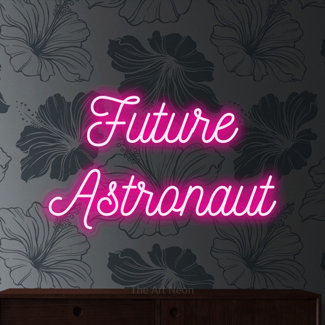 Hot pink script-style LED neon sign reading "Future Astronaut" against grey floral wallpaper for nursery décor