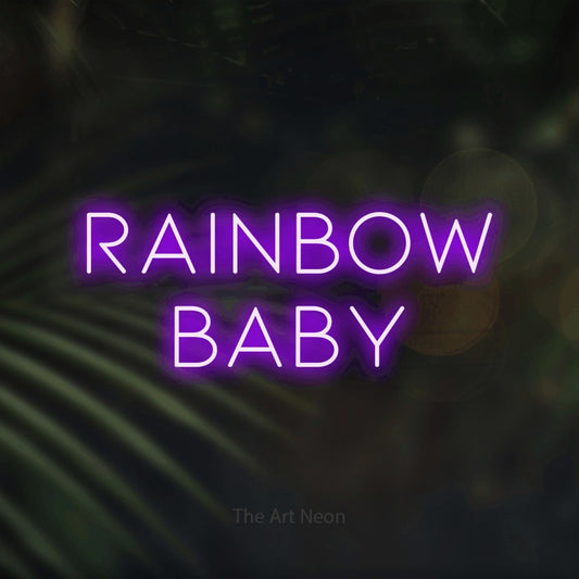 Purple LED neon sign reading "Rainbow Baby" against dark blurred palm leaves for nursery décor