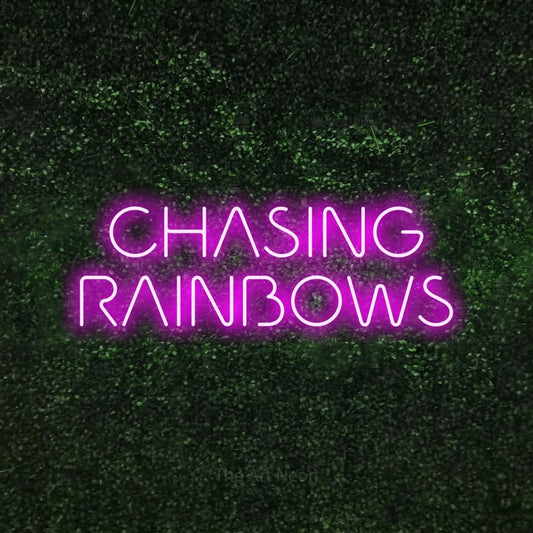Pink LED neon sign reading "Chasing Rainbows" against a textured green moss wall for nursery décor