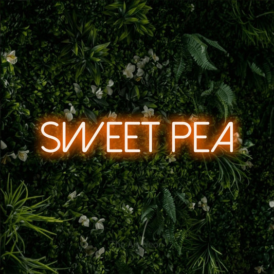 Orange LED neon sign reading "Sweet Pea" against a leafy green wall for nursery décor