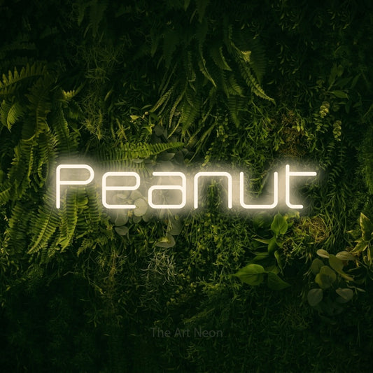Warm white LED neon sign reading "Peanut" against a moss-covered green wall for nursery décor